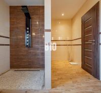 A bathroom in a family house with a wooden decor floor and a shower enclosure.