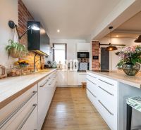 A kitchen in a family house with brick cladding and a wooden decor floor.