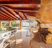 There is a covered terrace with a garden grill and a wooden-patterned floor in the exterior of the family house in Nitra.