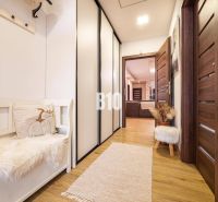 A hallway in a family house with a wooden decor floor, a bench, and cabinets.