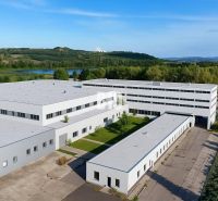 Production premises in Levice with a landscaped area, surrounded by greenery and a pond.
