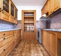 A kitchen in a family house with wooden cabinets and tiled flooring.