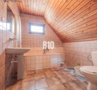 A bathroom in a family house with ceramic tiles and a wooden ceiling.