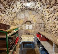 Stone cellar with shelves and a table with a tablecloth, suitable for storage.