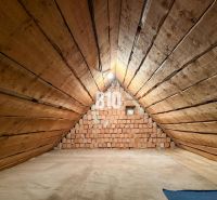 Attic space with wooden walls and a brick wall in a family house.