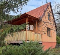 A family house in Vlkas surrounded by greenery, traditionally sloped roof, wooden balcony.