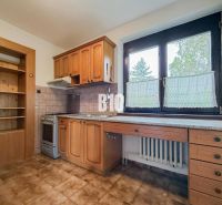 A kitchen in a family house with wooden cabinets and a large window, a floor with a wooden decor.