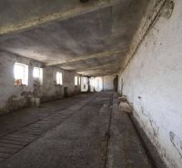 Abandoned industrial spaces with peeling plaster and narrow windows.
