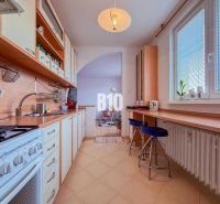 A kitchen in a 3-room apartment with a long work counter and a gas stove.
