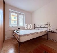 A bedroom in a 3-room apartment with a bed and a wooden decor floor.