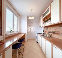 A bright kitchen in a 3-room apartment with bar stools and plenty of storage space.