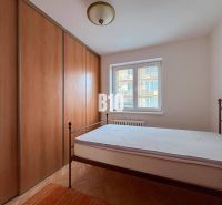 A bedroom in a 3-room apartment with a bed, built-in wardrobe, and flooring with a wooden decor.