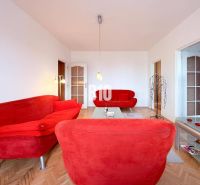 Living room with red sofas and a wooden decor floor in a three-room apartment.