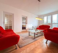 Living room in a 3-room apartment with a red sofa and a floor with a wooden decor.