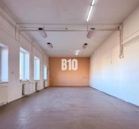 Interior of commercial premises with windows, radiators, and white walls.