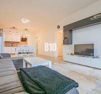 Living room with kitchen, white furniture, sofa and floor with wood decor.
