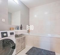 Bathroom with a bathtub, sink, and washing machine in a 3-room apartment.