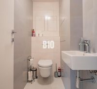 A bathroom in a 3-room apartment with simple light tiles and sanitary equipment.