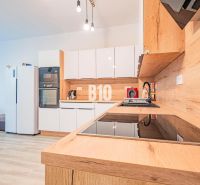 A kitchen in a 3-room apartment with glossy white cabinets and a wood-patterned floor.