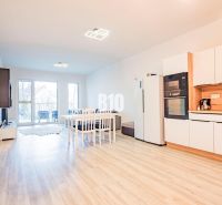 A kitchen in a 3-room apartment with a wooden decor floor and a dining table.