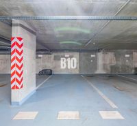 Underground parking in Nitra with marked parking spaces and concrete pillars.
