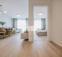 Interior of a 2-room apartment with a wooden decor floor, dining table, and bed.