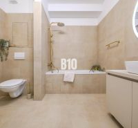 A bathroom in a 2-room apartment with beige tiles, a built-in bathtub, and a wall-mounted toilet.