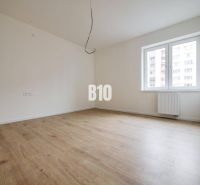A room in a three-room apartment with a wooden decor floor and a large window.