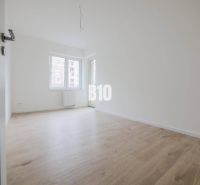 A room with a wooden decor floor in a 3-room apartment and large windows.