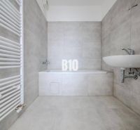 Bathroom with a bathtub and a sink in a 3-room apartment with modern tiles.