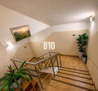 The interior of a building with flowers, a staircase, and a picture of nature on the wall.