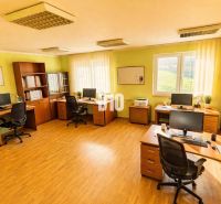 An office in a building with a wooden floor decor, computers, desks, green walls, shelves.