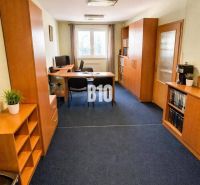 An office with a blue carpet and wooden furniture in a building.