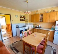 A kitchen in a family house with wooden cabinets and a dining table.