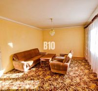 A living room with brown seating furniture and a carpet in a family house.