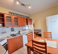 The kitchen of a 3-room apartment with wooden decor cabinets and a dining table.