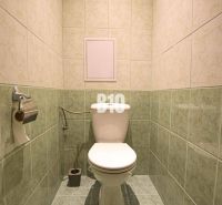 A toilet with tiled walls in a 3-room apartment.
