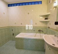 A bathroom with a bathtub and green tiles in a 3-room apartment.