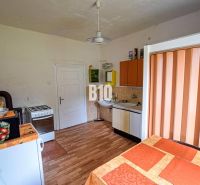 A kitchen in a family house with a tiled stove, a cooker, and a floor with a wooden decor.