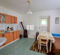 A kitchen in a family house with simple furniture and tiles.