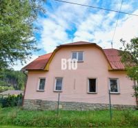 A family house in Makov with a stone foundation and a red roof surrounded by greenery.