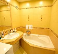 Bathroom with yellow tiles, a bathtub, a sink, and a mirror in a 3-room apartment.