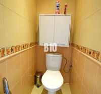 A toilet with beige tiles and a wall cabinet in a 3-room apartment.