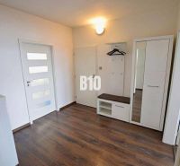 The entrance hall of a 3-room apartment with a wooden decor floor, a wardrobe, and a coat rack.