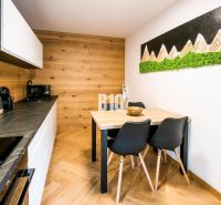 A kitchen in a studio apartment with a wood-patterned floor and art on the wall.