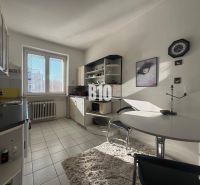 Kitchen in a 2-room apartment with white cabinets, a window, and a dining table.