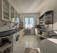 A kitchen in a 2-room apartment with white cabinets and a black countertop.