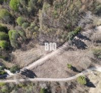 An aerial view of residential plots in Žilina surrounded by trees and a road.