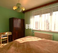 A bedroom in a family house with a window, curtains, a wardrobe, and a table.