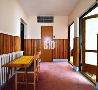 Hallway in a family house with wooden paneling, a table, and a chair.